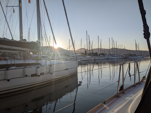 Sailboats docked at a marina with mountains in the background.