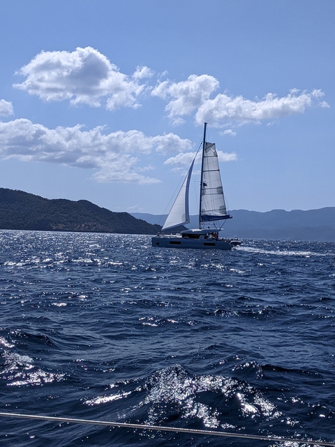 Sailboat on the open sea with mountain views.