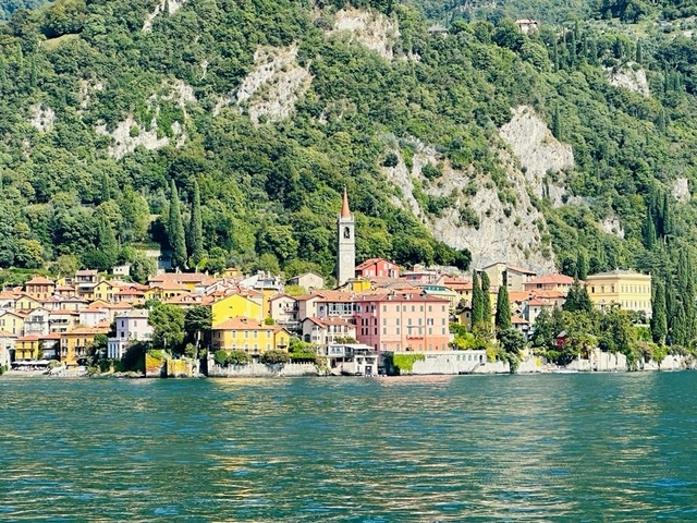 Colorful town with church tower and cliffs in the background.