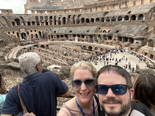 Couple at the Colosseum with a view of its interior and crowd.