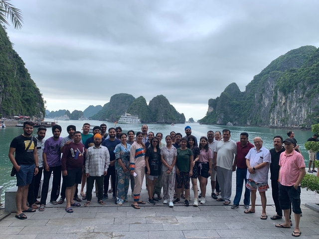 Large group posing in front of scenic bay and karst formations