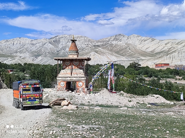       Chorten stupa with prayer flags against a mountain backdrop.
  