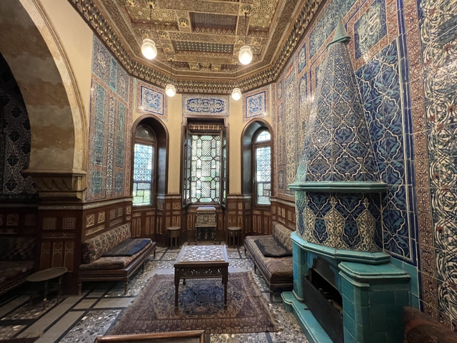 A richly decorated interior with intricate tiles and arched windows.