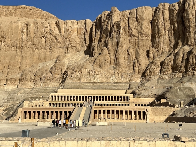 Temple of Hatshepsut carved into a cliff, visitors present in the foreground.