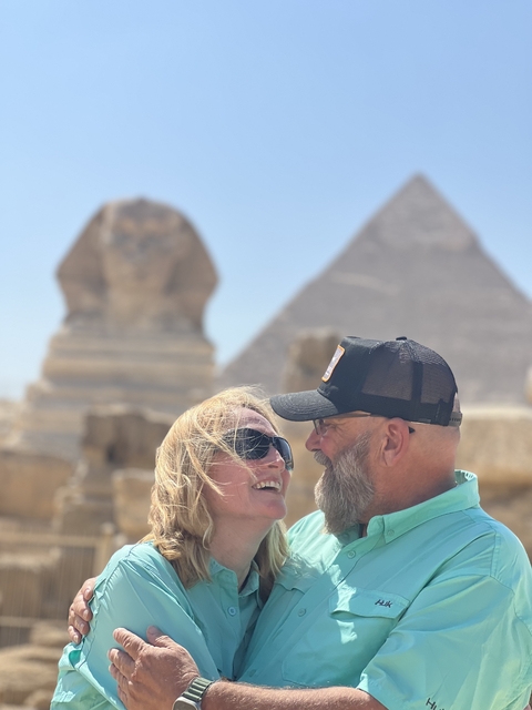 A couple smiling with the Sphinx and Pyramid in the background.