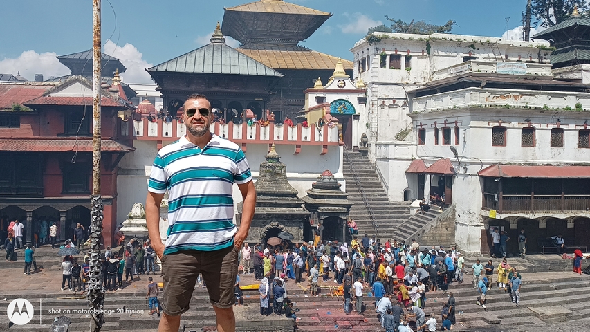       Person posing with a crowded temple in the background.
  