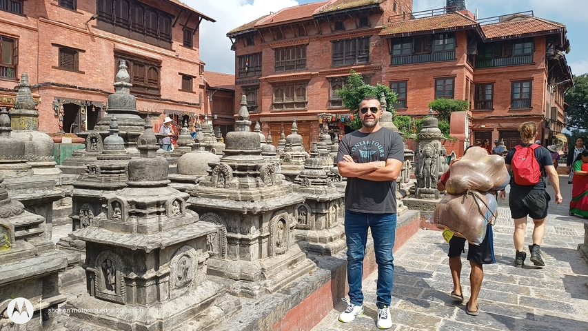       Person standing among traditional Nepalese architecture and stupas.
  