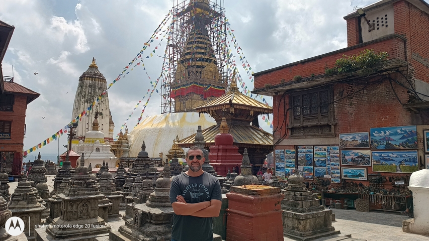       Swayambhunath Stupa with flags and a person posing.
  