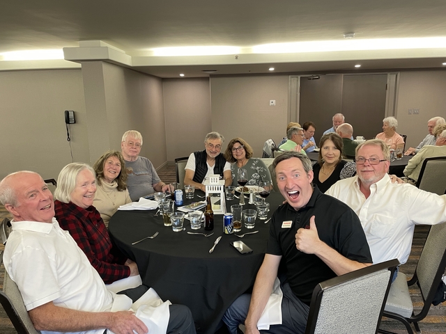       People sitting around a large dining table during a social gathering.
  