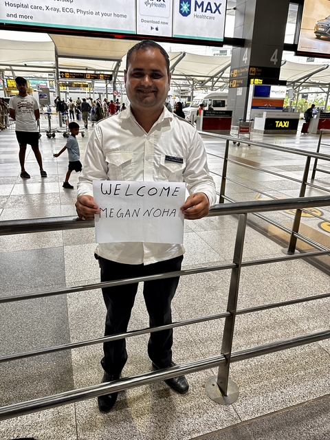      A person holding a welcome sign at an airport.
  