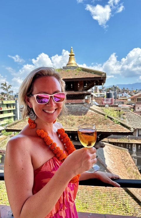       A woman enjoying a drink with a picturesque cityscape backdrop.
  