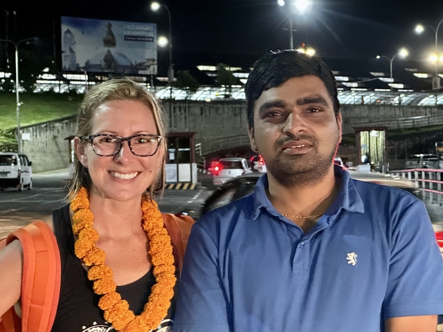 A man and woman posing with a nighttime backdrop.