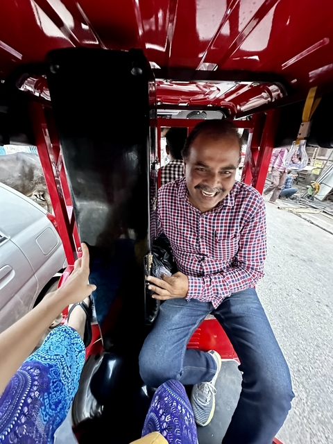 A man smiling in a rickshaw.