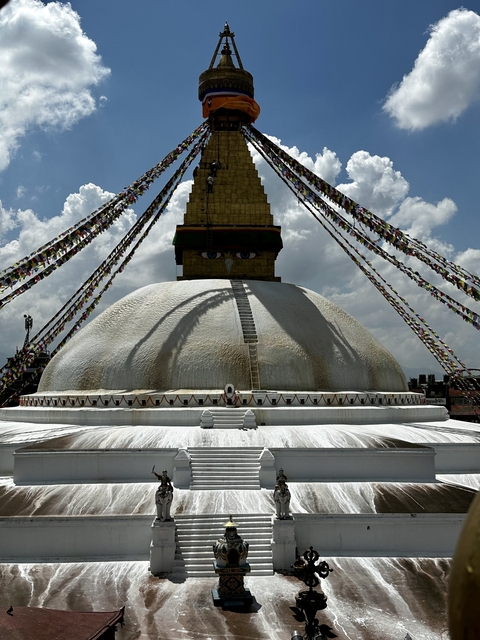       The Boudhanath Stupa with prayer flags under a sunny sky.
  