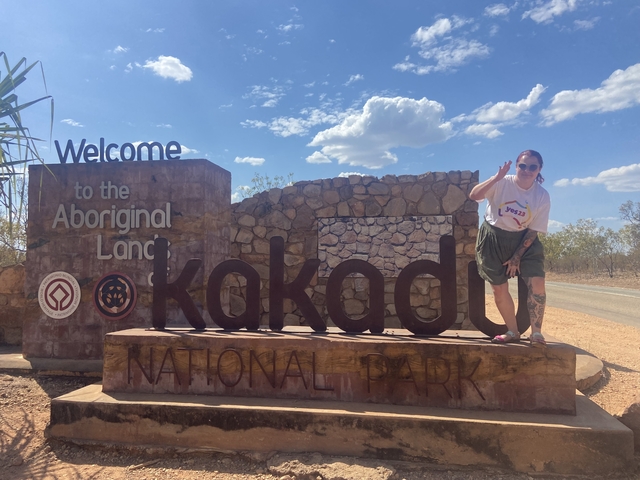 Person posing by the sign of Kakadu National Park.