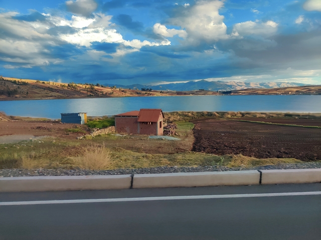       Lakeside with small structures and distant mountains.
  
