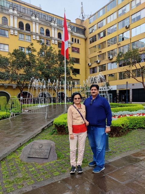 Couple in front of a fountain with a park setting.