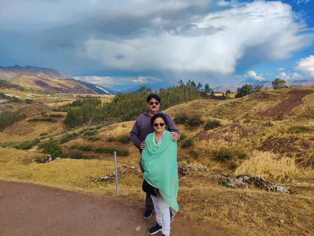 Couple standing in a hilly landscape with distant mountains.