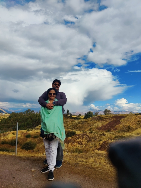 Couple posing in a field with mountains in the background.