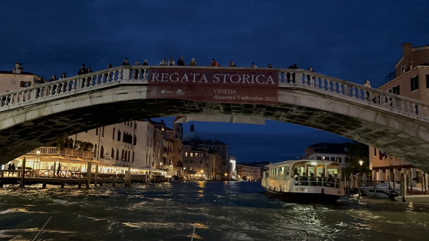       Night view of a bridge over a canal in Venice.
  