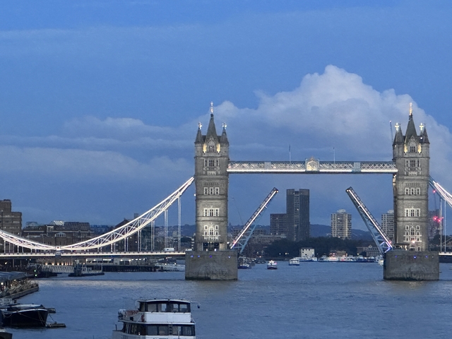       Twilight view of Tower Bridge with its bascules raised.
  