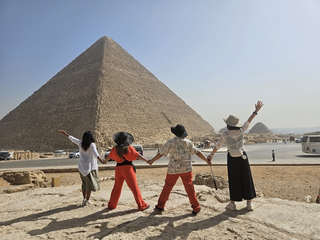 A group of people facing the Great Pyramid of Giza.