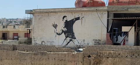       A mural of a person throwing flowers on a building wall.
  