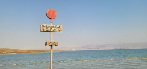       A sign reading 'The Lowest Point On Earth' by the Dead Sea.
  