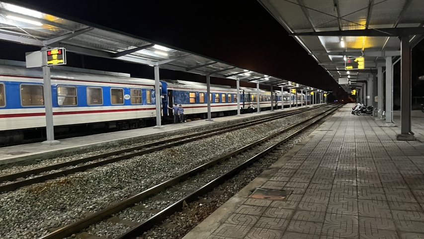       Train station platform at night with a parked train.
  