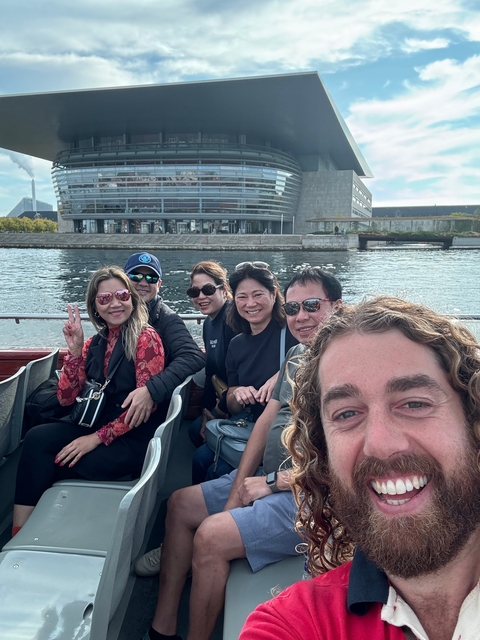 Group of people on a boat ride with modern building backdrop.
