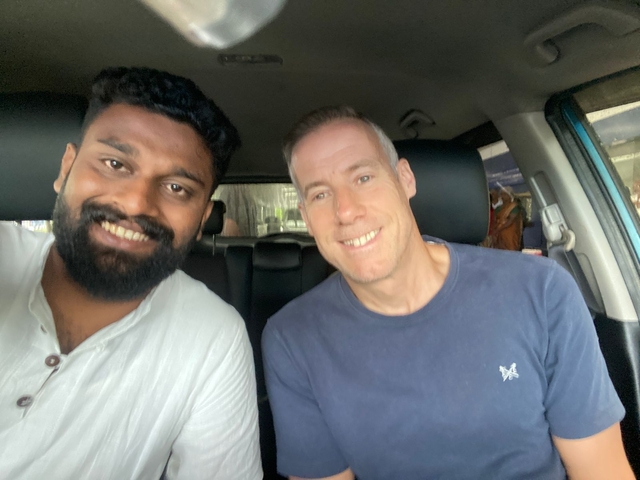 Two people smiling while sitting inside a car.