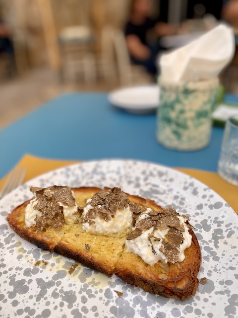      Plate of food topped with truffles on an outdoor table.
  
