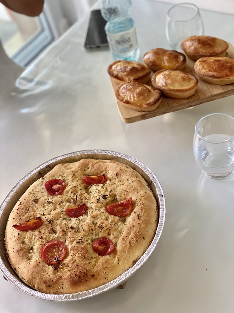       Focaccia bread with cherry tomatoes next to a glass of water.
  