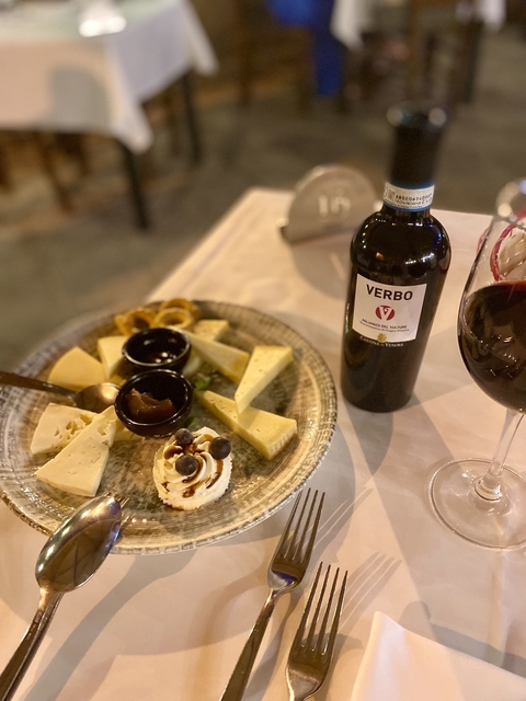      Cheese platter with red wine on a table.
  