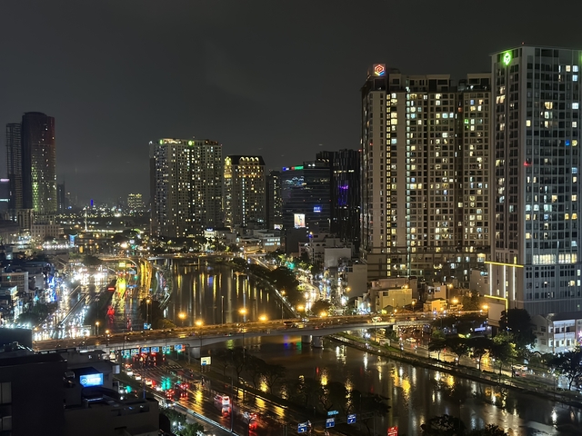 Night view of buildings and a lit-up bridge over water.