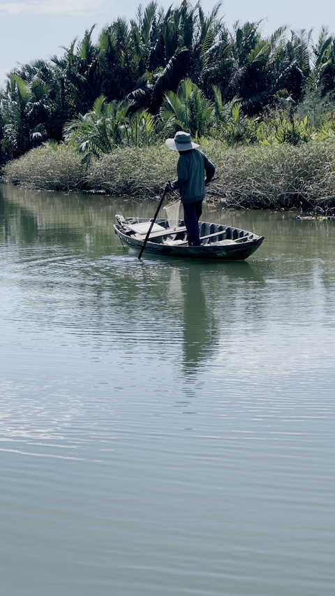 Person paddling a small boat on a calm river.
