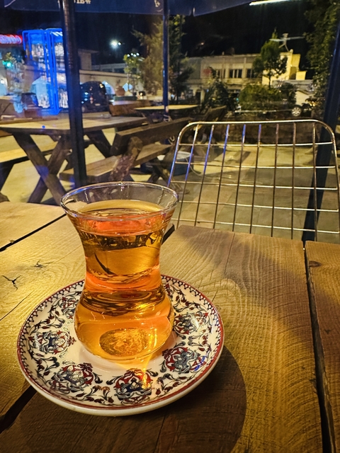       Glass of tea on a beautifully decorated saucer on a wooden table.
  