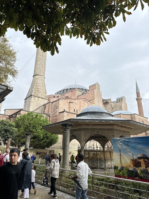       Hagia Sophia with its domes and minarets under a cloudy sky.
  