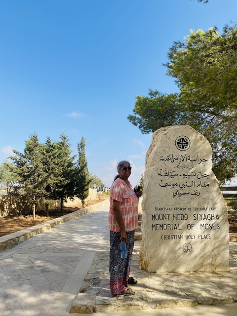 Person standing next to a rock with text at Mount Nebo.