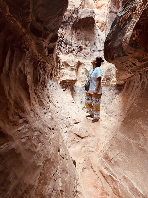       Person standing inside a narrow rock formation.
  