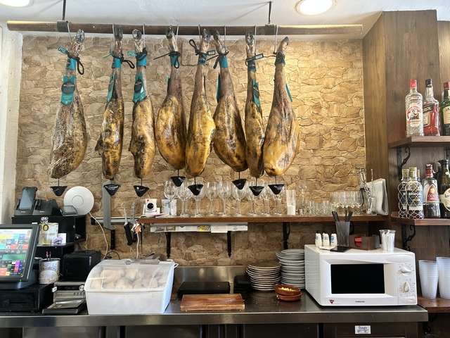 Ham hanging above a counter in a shop.