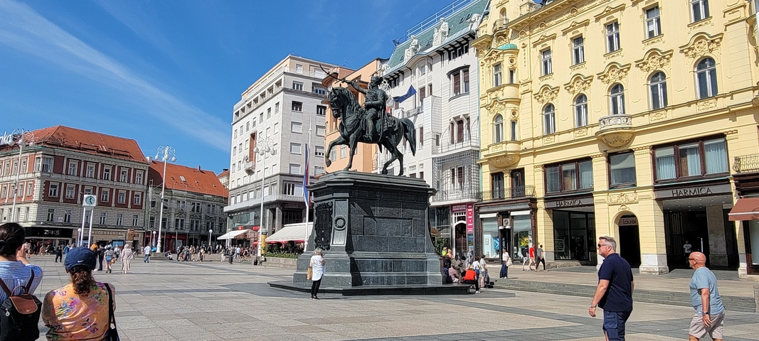 Central city square with a statue and surrounding buildings.