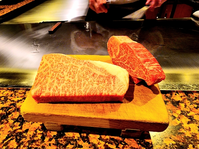Two pieces of marbled meat on a wooden board.