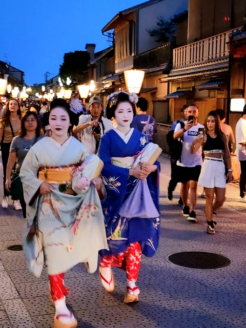 Geishas walking through a busy street.