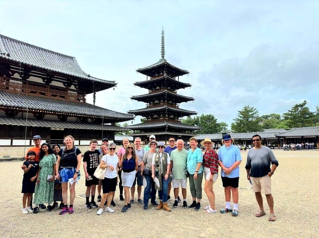 Large group posing in front of a traditional pagoda.