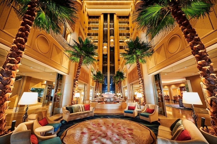 Elegant hotel lobby with palm trees and luxurious furnishings.