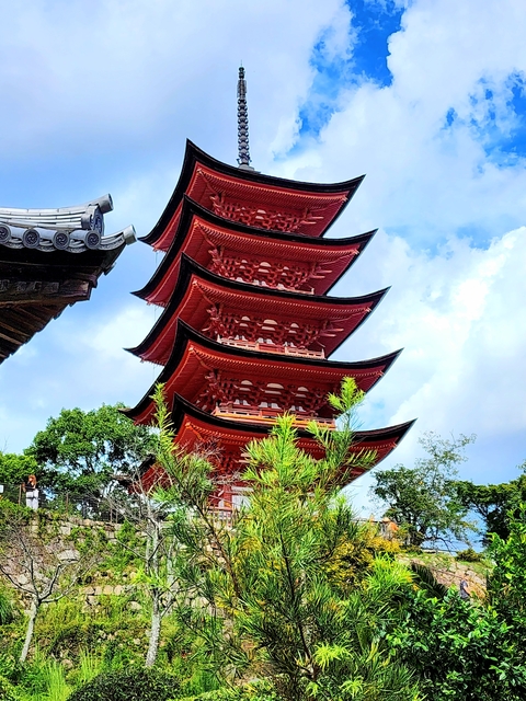 Red pagoda set against a blue sky with surrounding trees.