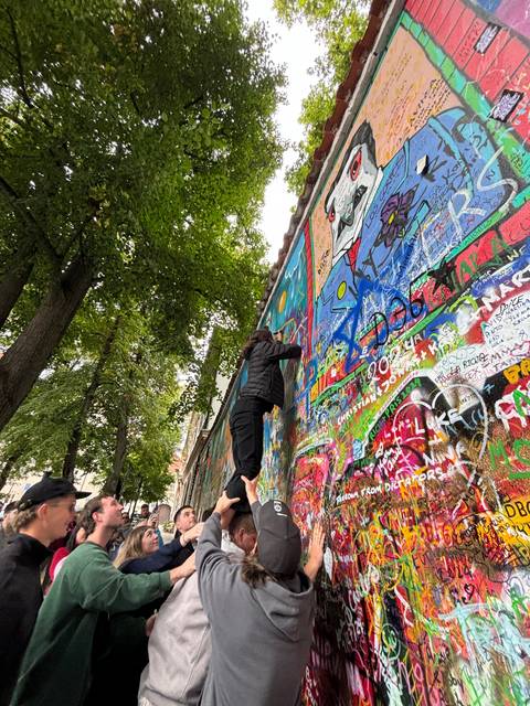 Tourists interacting with a colorful graffiti wall.