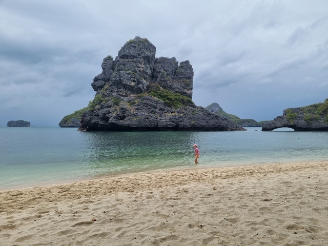 A solitary person on a beach with rocky formations.