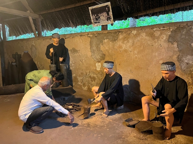       People interacting with life-sized diorama in a traditional setting
  